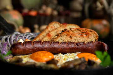 Sausage and fried eggs with toasted bread, mushrooms and onions served in cast iron dish. Selective...