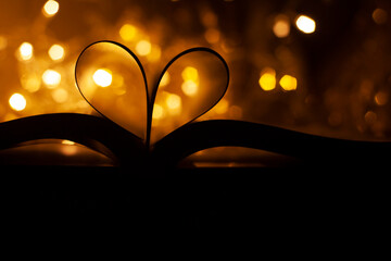 Heart shaped book pages on shiny bokeh background