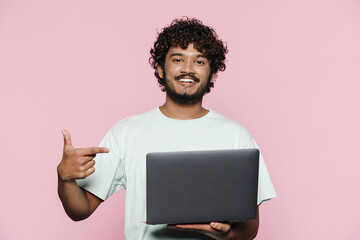 Young middle eastern man smiling while pointing finger at his laptop