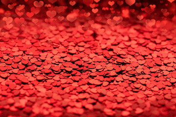red background with shiny confetti sequins in the form of bokeh hearts. blank layout for valentine's day, greeting love cards or gifts and invitations to a wedding celebration