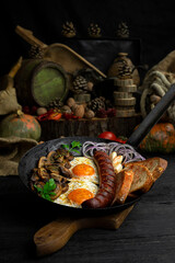 Fried eggs and sausage with mushrooms served in cast iron pan in the kitchen