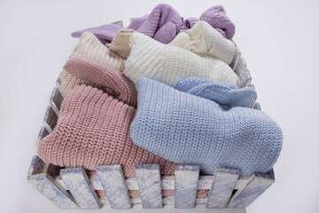 Fototapeta na wymiar in a wooden tray there are many sweaters of different colors, a large assortment, shopping concept