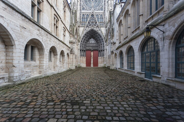 Wide angle view of cobblestone courtyard with red doors in a vintage gothic church