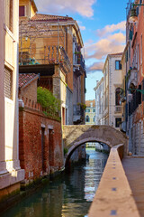 Venezia, Veneto, Italy. Vintage stone bridge over canal between houses of traditional italian architecture. Romantic place and evening sunset.
