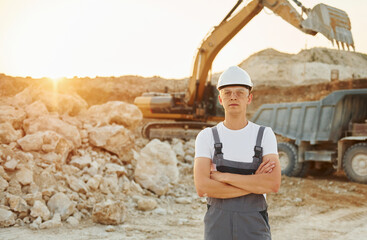 Fototapeta premium Standing with arms crossed. Worker in professional uniform is on the borrow pit at daytime