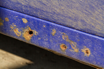 Corrosion and rust of a car. Rust has punctured a threshold of a blue car.