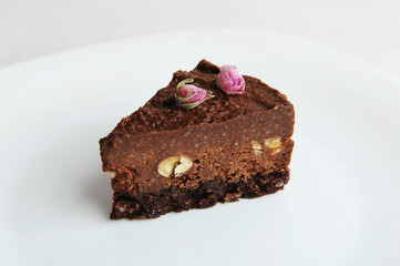 Slice of vegan chocolate nut cake on white plate close-up