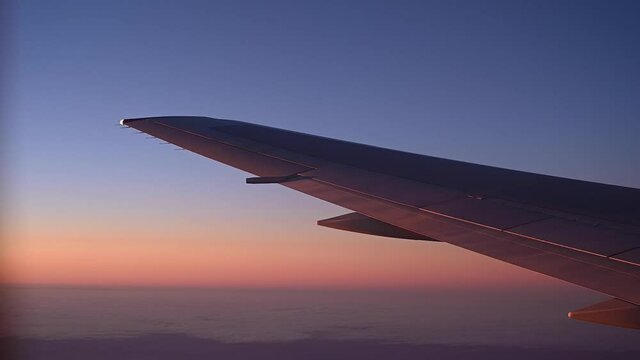 View of the wing of an airplane during flight from the window at sunset.