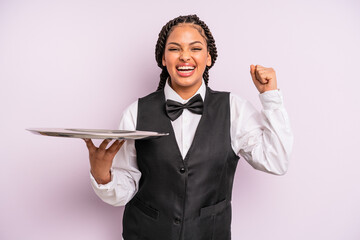 afro black woman feeling shocked,laughing and celebrating success. waiter with a tray - obrazy, fototapety, plakaty
