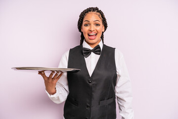 afro black woman looking happy and pleasantly surprised. waiter with a tray