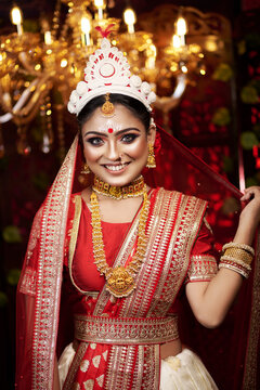 Portrait of very beautiful young Indian bride in luxurious bridal costume with makeup and heavy jewellery looking at studio. Wedding fashion.