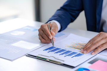 Asian male finance staff Is explaining the performance from the company's rapidly growing bar graph this year. To his boss On the desk at the office, Finance concept
