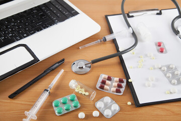  Doctors desk. Stethoscope, computer, notebook pills, on wooden background.