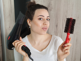 Stylish pretty woman holding a dryer and comb.