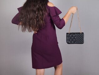 Fashion woman in a beautiful dress, with a holding handbag.