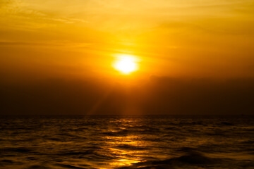 Beautiful long exposure of amazing sunset with silhouette smooth wavy sea and cloud. orange horizon with sunset sky.