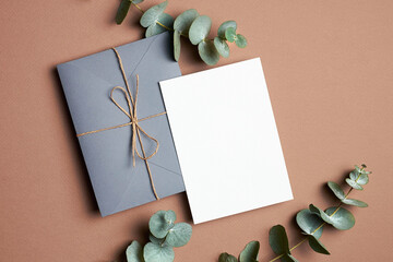 Wedding invitation or greeting card mockup with envelope and natural eucalyptus twigs