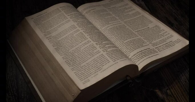 A  page in the bible is being turned over, contrast Night atmosphere