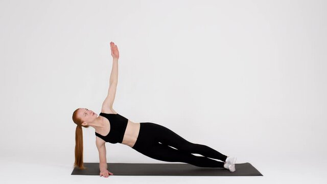 Athletic Young Woman Doing Side Plank Rotations Exercise While Training In Studio