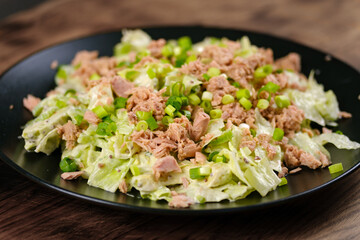 Tuna Salad with Lettuce, spring onions and dijon mustard salad dressing served on black plate