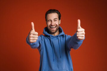 Young bristle man winking and smiling while showing thumbs up