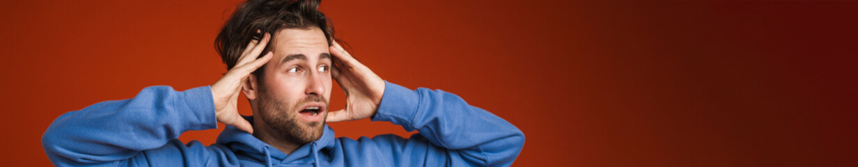 Fototapeta premium Young man holding his head while expressing surprise