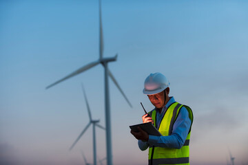 Service engineers checking wind turbine on tablet on  wind turbine farm Power Generator  on...