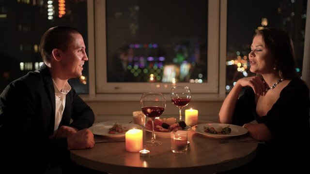 romantic dinner at home for two. A loving couple sitting at a table close-up portrait. concept for celebrating valentine's day or anniversary. Red wine and candles on the table.