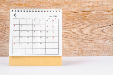 June 2022 desk calendar on wooden table.