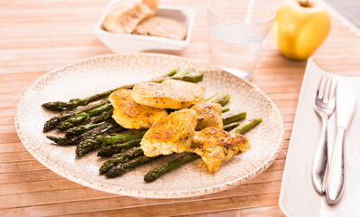 cooked dish. Chicken nuggets with green asparagus on plate