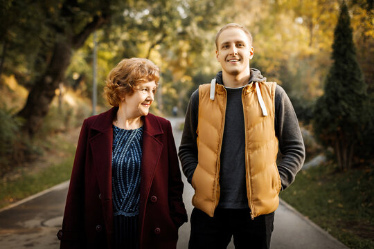 Russian caucasian mature mother with her adult son walking autumn outdoor.