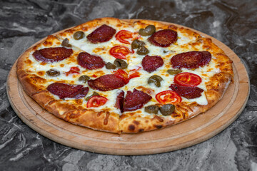 Pizza with green olives, Turkish sausage and cheese on a cutting board