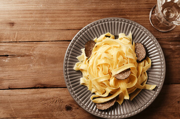 Tagliatelle italian pasta with cut fresh black truffles on vintage background.