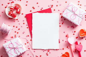 Romantic letter concept. Blank paper card mockup, red envelope, gifts, decoration on pink...