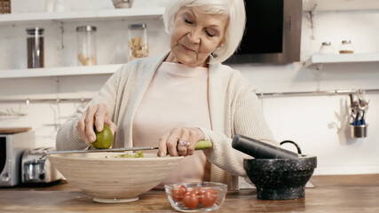 elderly woman grating lime to vegetable salad for thanksgiving dinner.