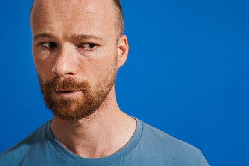 Ginger puzzled man with beard posing and looking upward