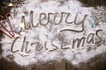 Inscription with Christmas on a wooden table flour sweets red white lights Christmas