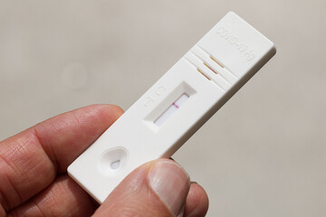 Close up of a hand holding rapid covid-19 test with a negative result. Express self-test coronavirus testing at home.