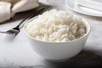 Long-grain boiled rice in a white cup on a light background