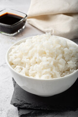 Long-grain boiled rice in a white cup on a light background