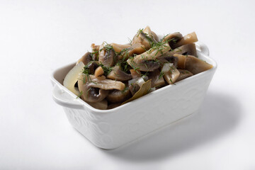 Homemade pickled mushrooms in a white cup on a white background for insulation