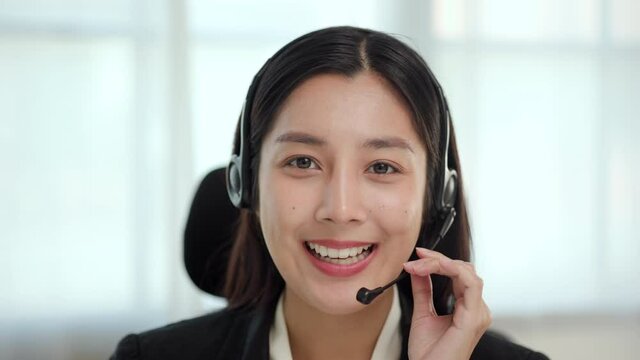 Call center and helpful customer service with online teacher concept. Happy asian business woman receptionist wear headphone video conference calling on computer talk by webcam in online chat