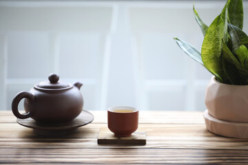 pottery teapot and tea cup and snake plant on brown wooden table