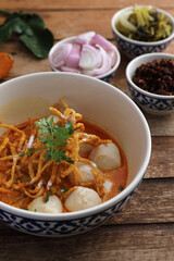 Local northern Thai food Egg noodle curry with meatballs on wood background