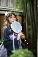 Beautiful young woman with dark blue Chinese lolita dress with Chinese garden