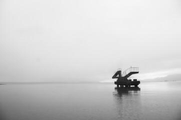 Obraz premium Natural landscape, black and white photo of stone pier over sea water on the beach.