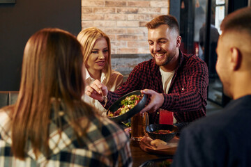 Having conversation. Group of young friends sitting together in bar with beer