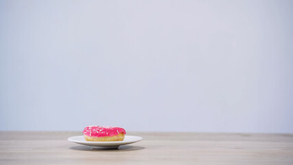 sweet glazed doughnut on plate isolated on grey.