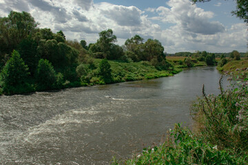 View of a turbulent section of a small river among fields and trees. The Upa River in Russia, the nature of the middle lane.