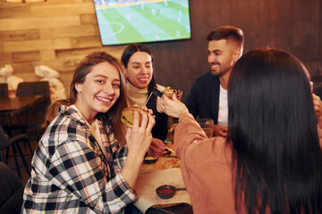 Talking with each other. Group of young friends sitting together in bar with beer